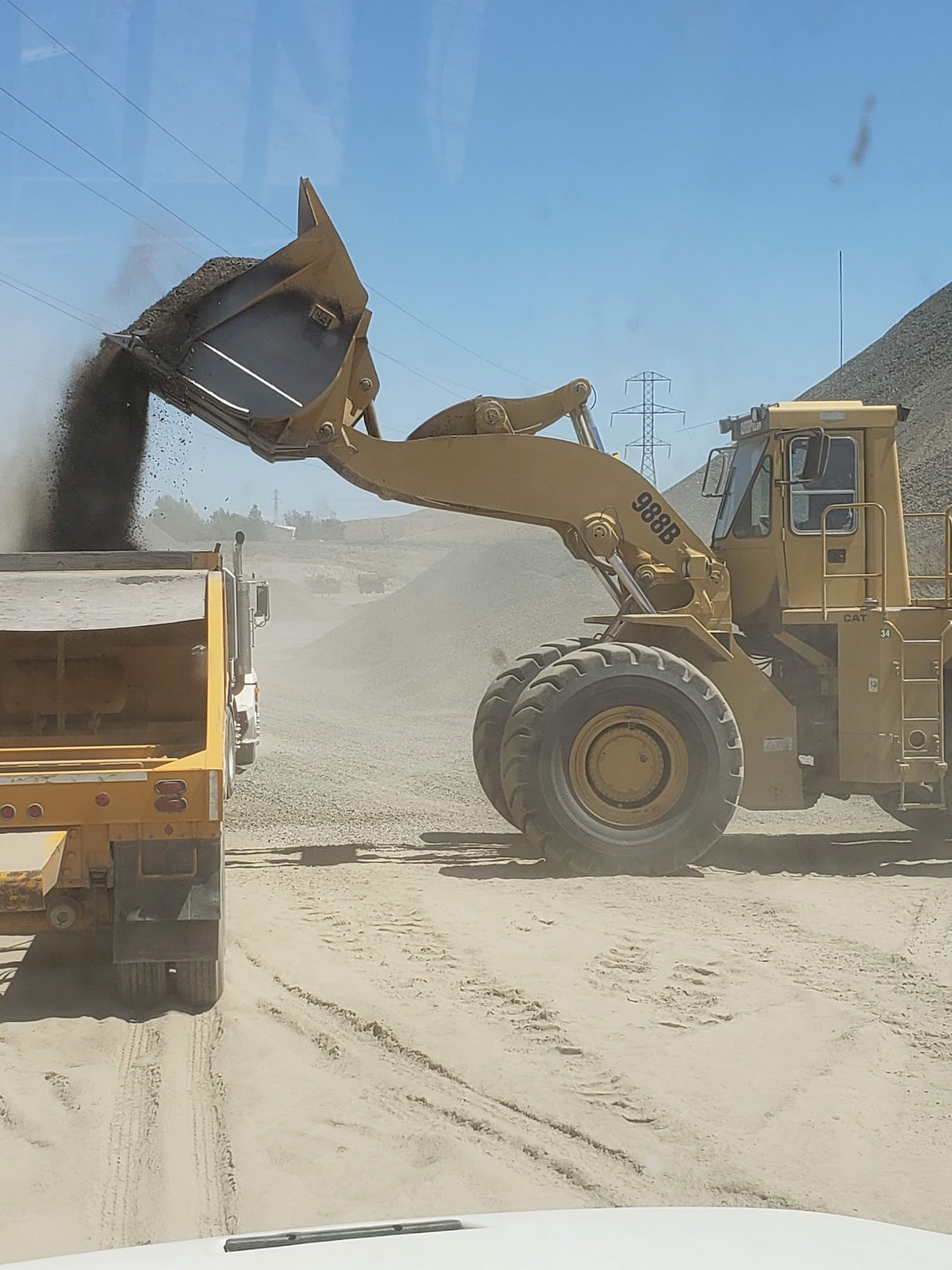 A CAT 988B wheel loader pouring gravel into a dump truck at the quarry