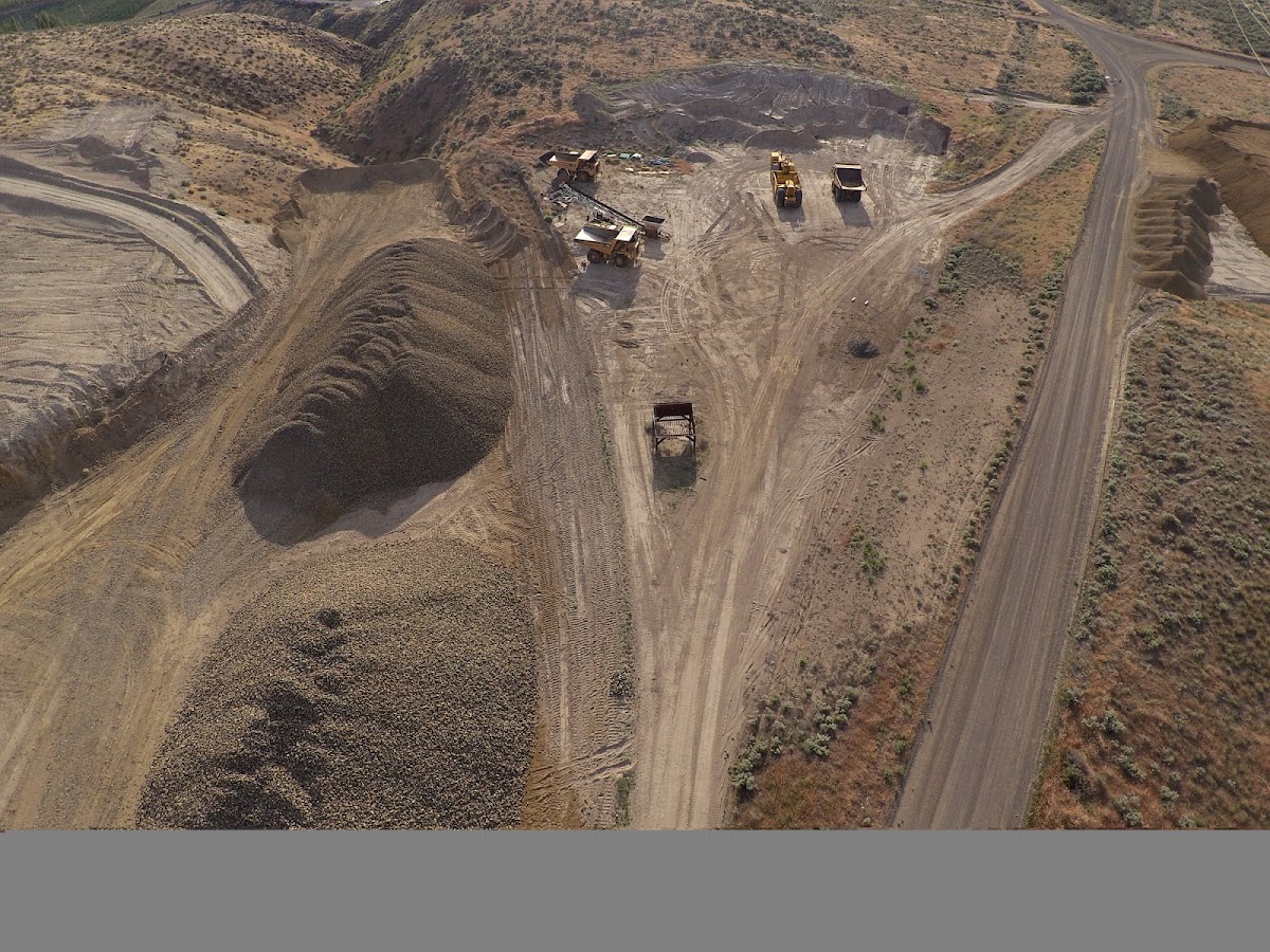 Graded stockpiles and haul trucks working the Olympia Quarry pit